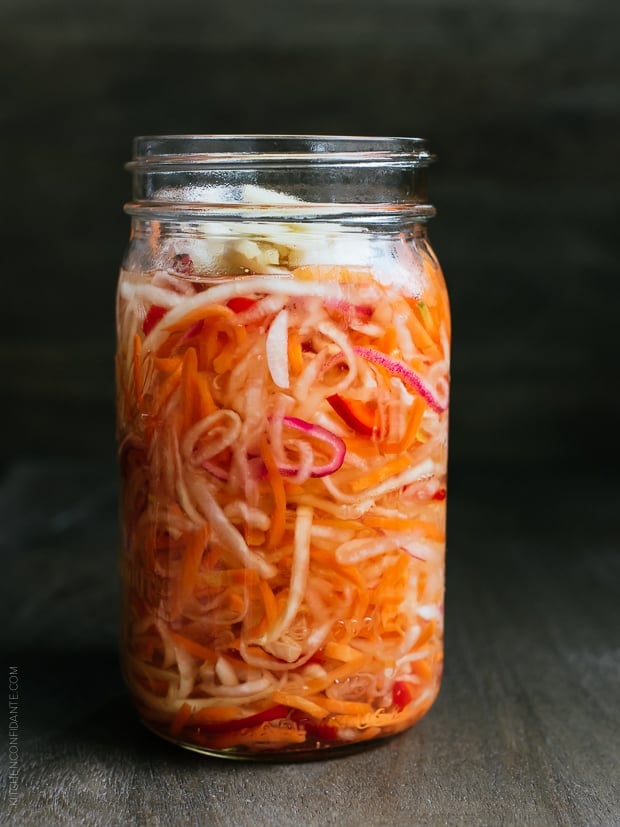 Glass jar filled with homemade Achara on a wooden surface.