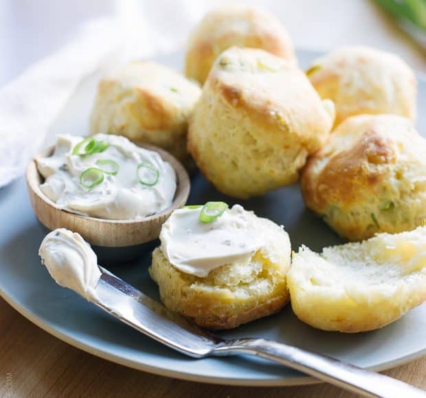 Cream Cheese and Green Onion Biscuits broken in half and slathered with soft cream cheese and garnished with green onions.