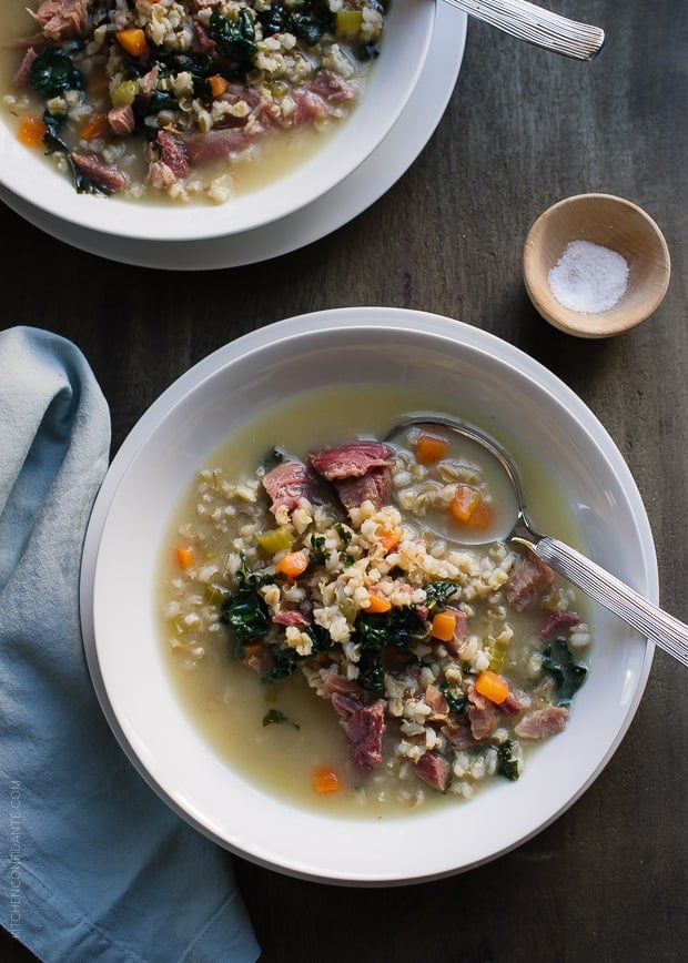 Two white soup bowls filled with Ham, Barley and Kale Soup made from a leftover ham bone.