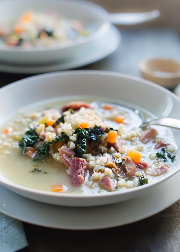 White soup bowl filled with Ham, Barley and Kale Soup made from a leftover ham bone.