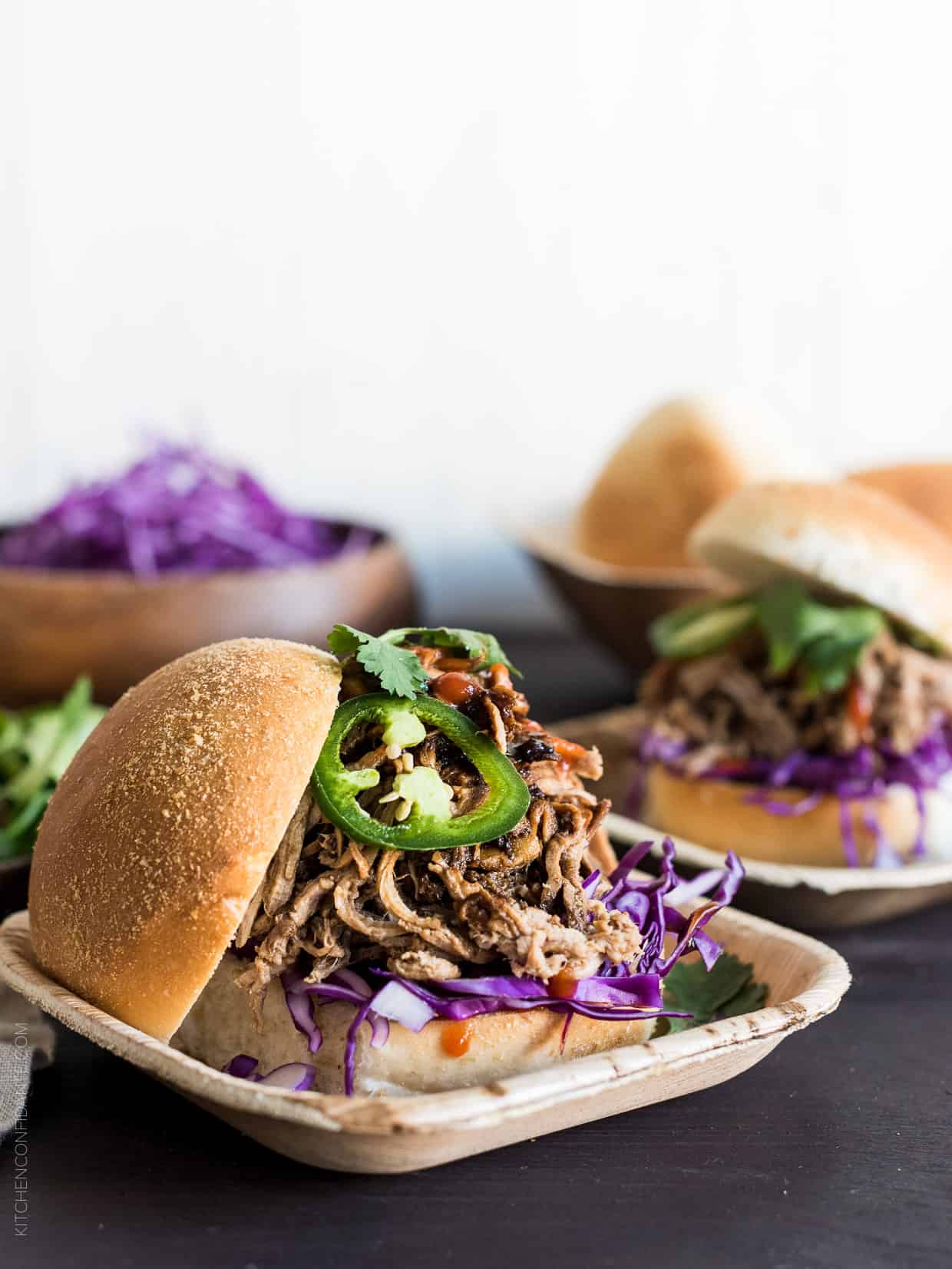 Filipino Adobo-style Pulled Pork Sandwich layered with red cabbage, a few leaves of cilantro and sriracha. 