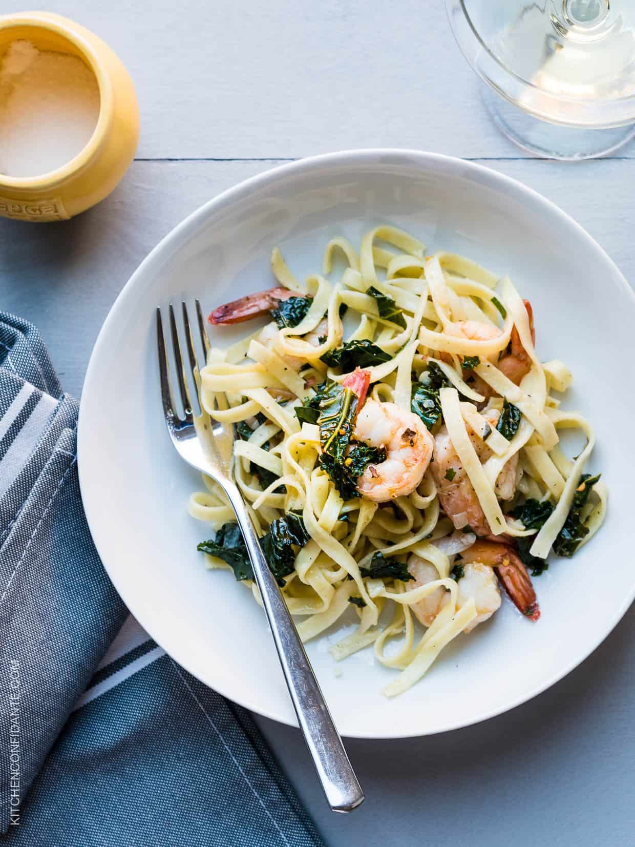 Freshly cooked linguine, leafy kale, and shrimp twirl together on a dinner plate to create Kale and Shrimp Scampi. 