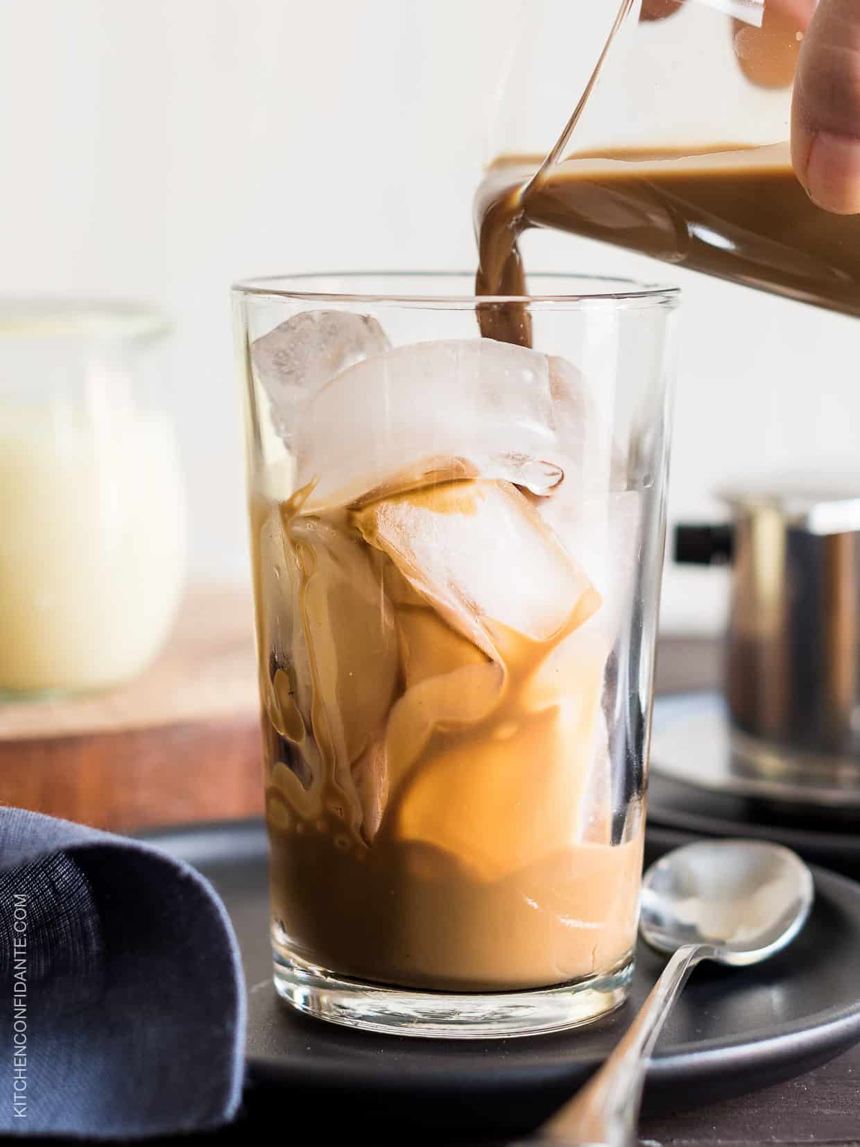 Pouring a coffee and condensed milk mixture over a glass of ice to make Vietnamese Iced Coffee. 