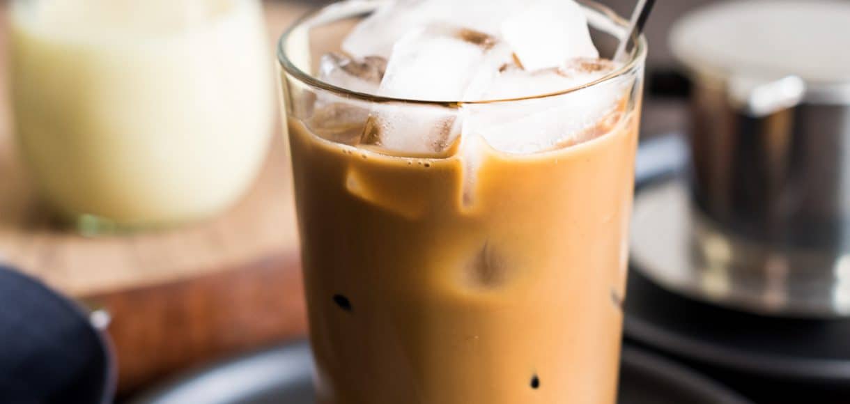 A tall glass of Vietnamese Iced Coffee (Ca Phe Sua Da) with a spoon to stir.