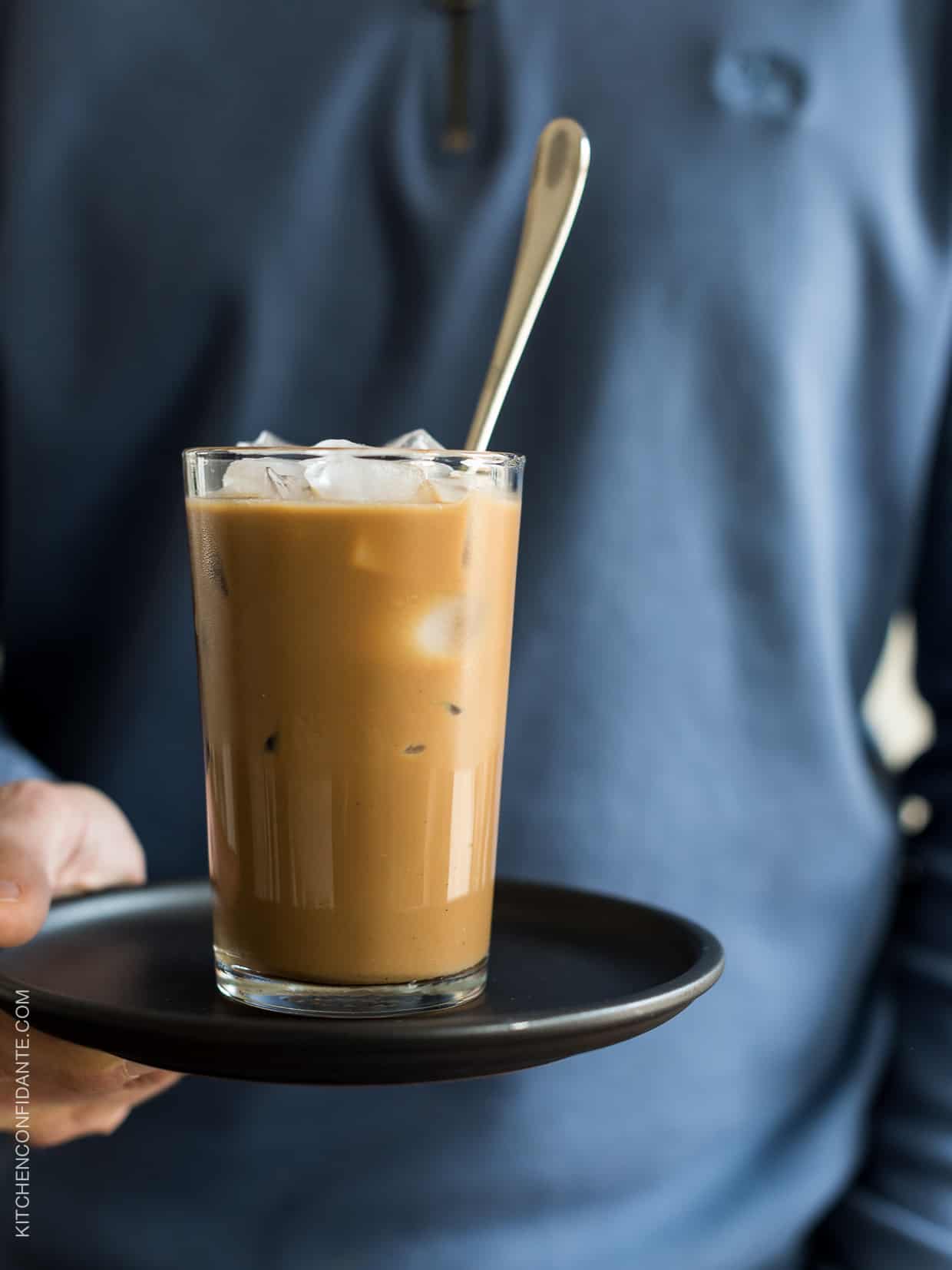 Holding a glass of Vietnamese Iced Coffee on a plate. 