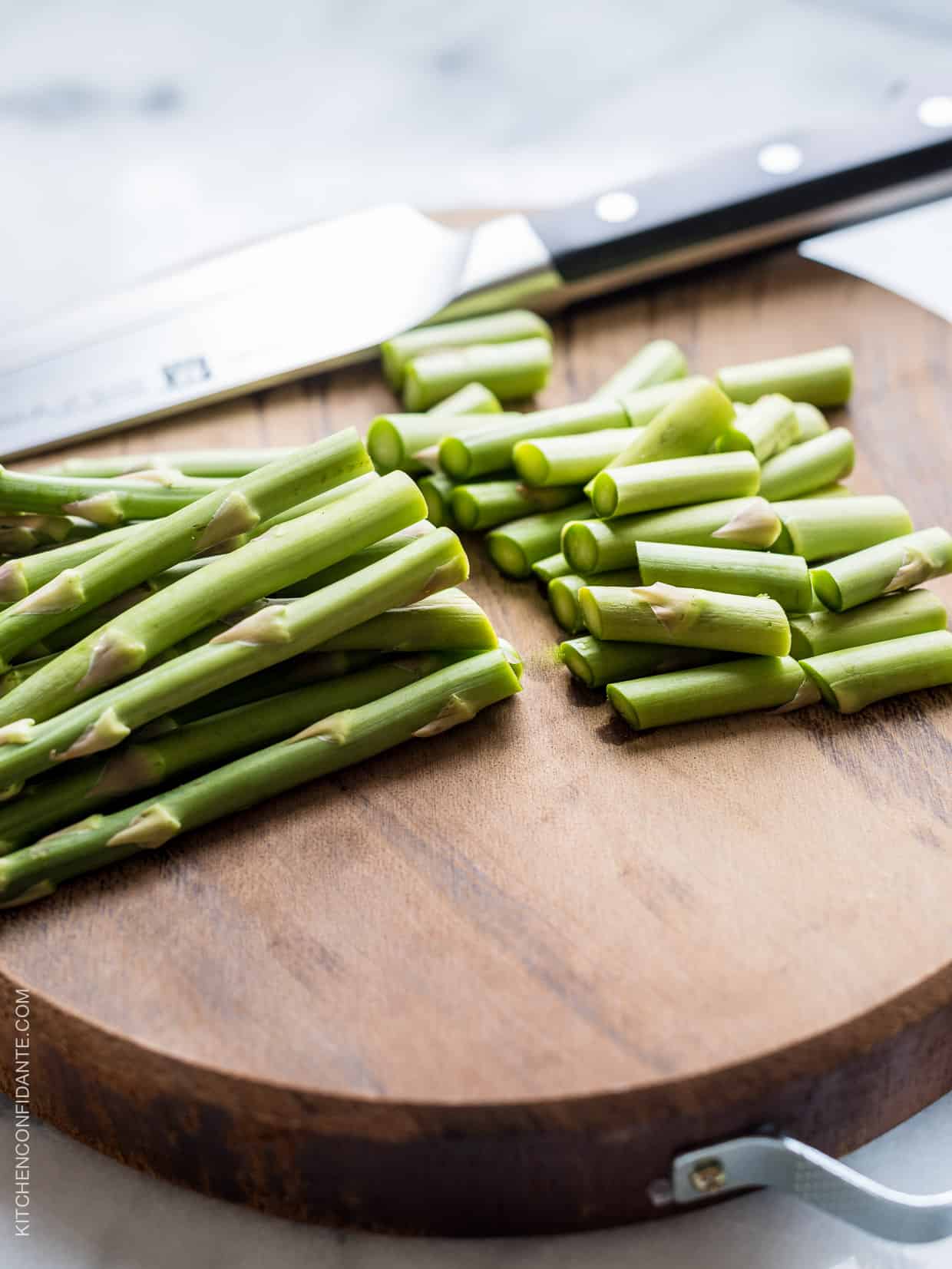 Chopping asparagus on a wooden surface for a springtime frittata.