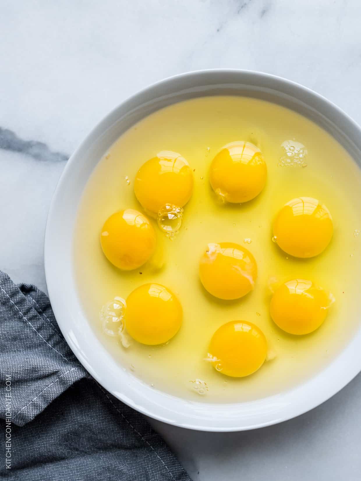 A white bowl filled with eight eggs--yolks and whites.