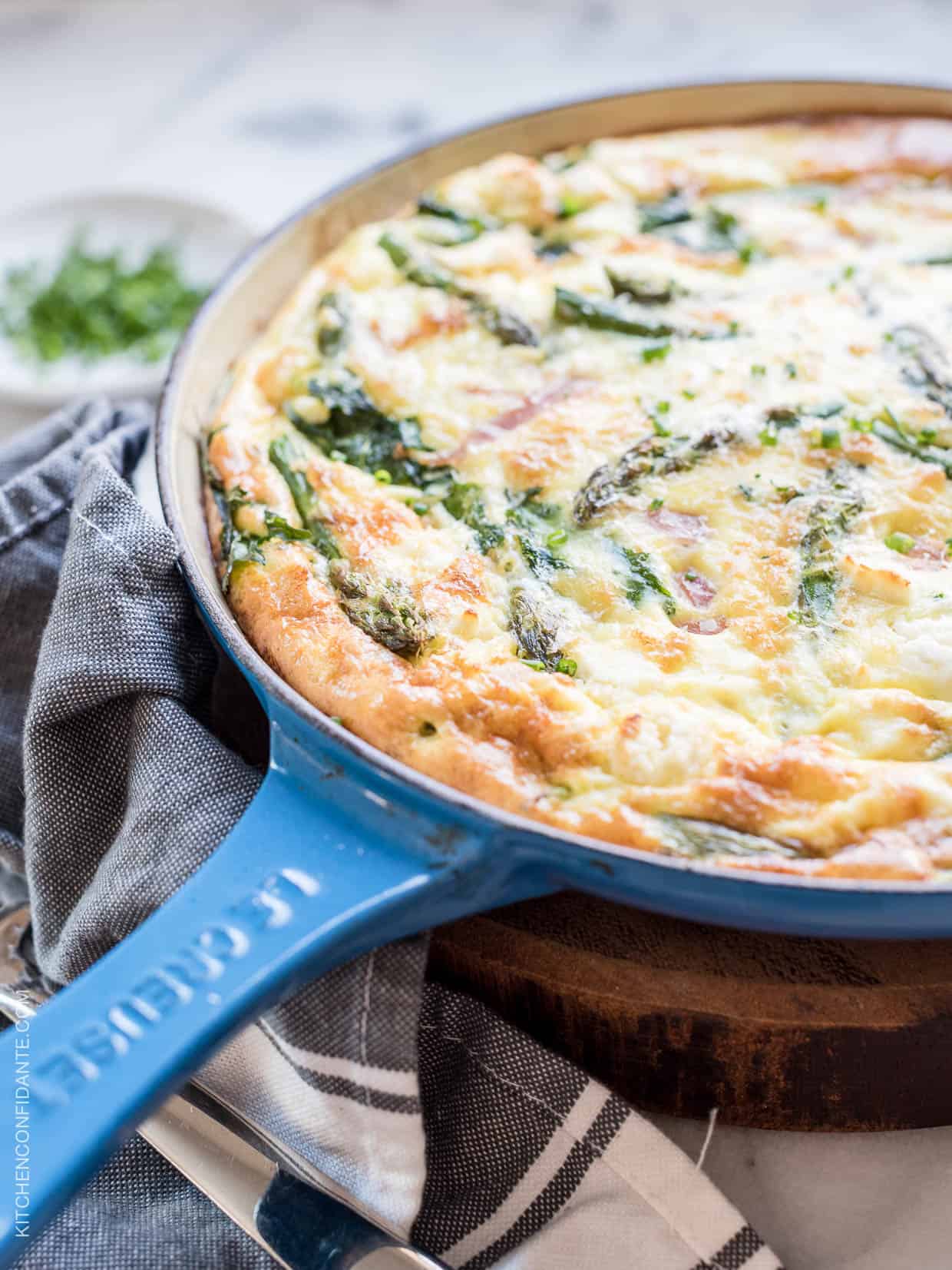 An Asparagus, Ham and Kale Frittata in a blue skillet.