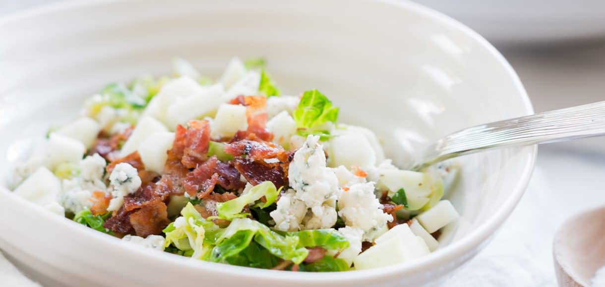 A white bowl filled with Shredded Brussels Sprouts Salad.