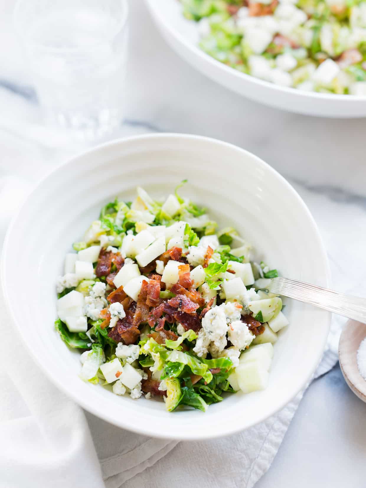 A white bowl filled with Shredded Brussels Sprouts Salad.