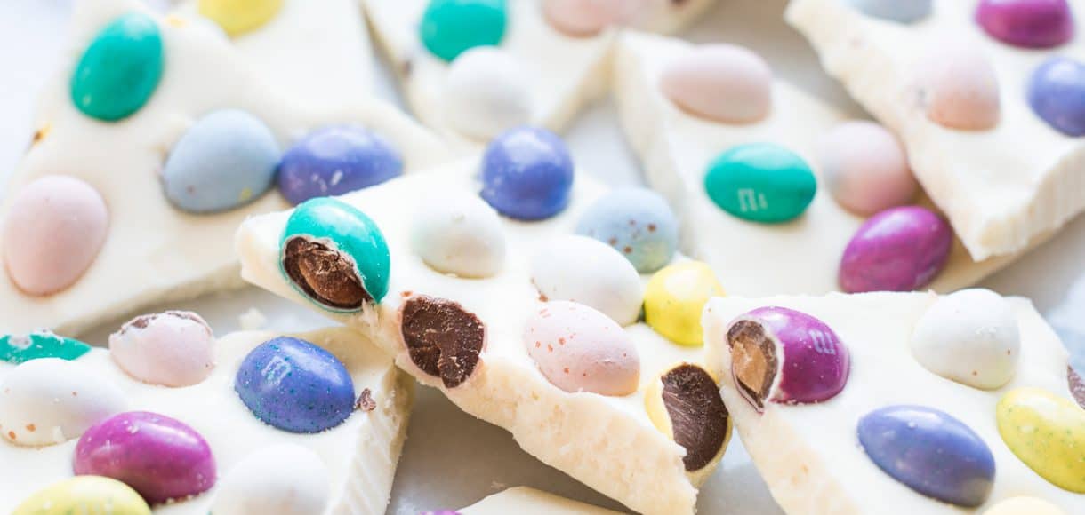 Pieces of colorful homemade White Chocolate Easter Bark on a white surface.