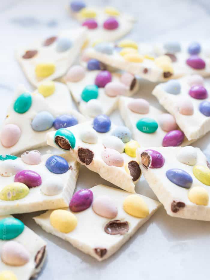 Pieces of colorful homemade White Chocolate Easter Bark on a white surface.