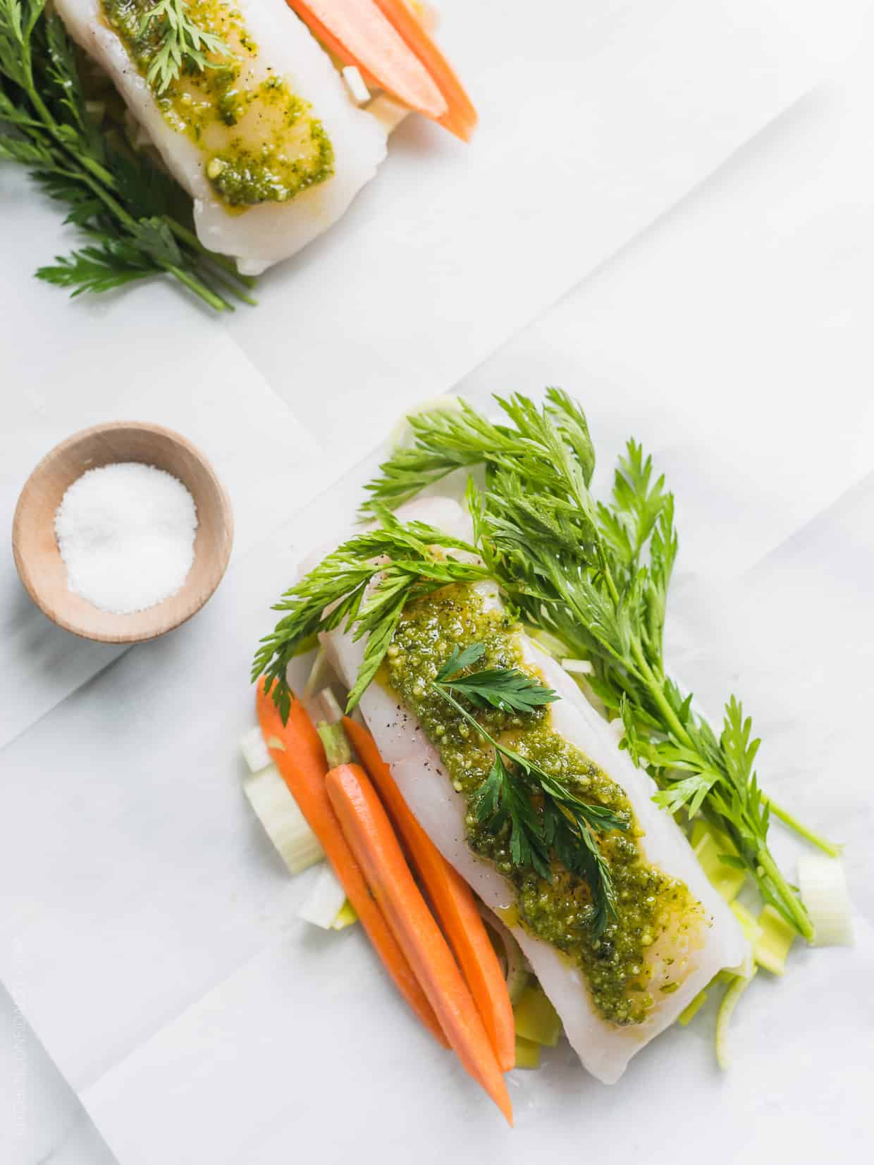 Baked halibut in parchment paper with carrot top pesto on top.