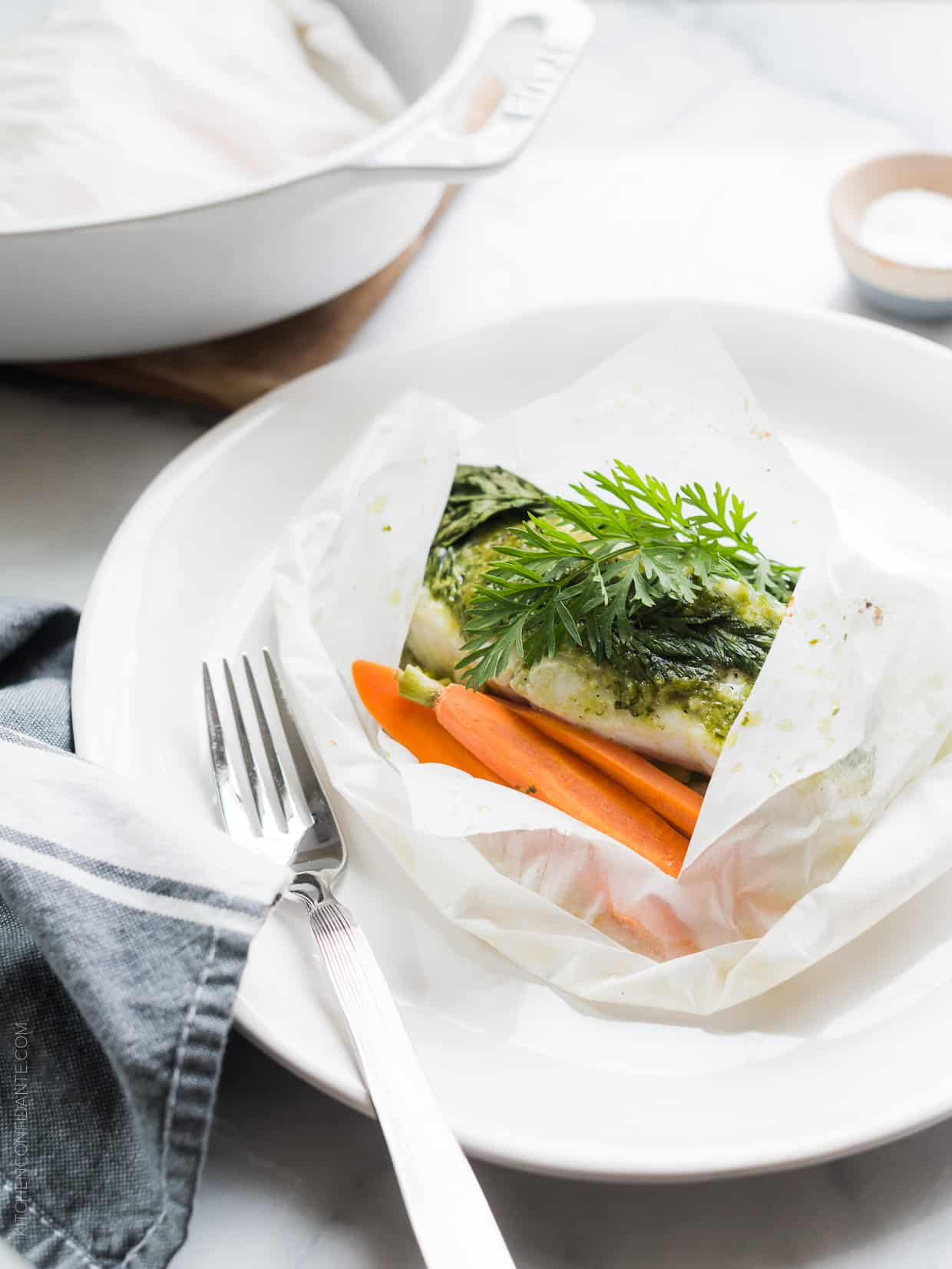 Baked halibut in parchment paper with carrot top pesto on top.