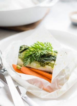 Baked halibut in parchment paper with carrot top pesto on top.