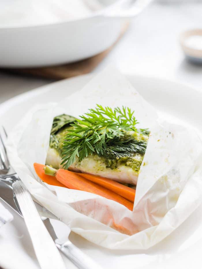 Baked halibut in parchment paper with carrot top pesto on top.