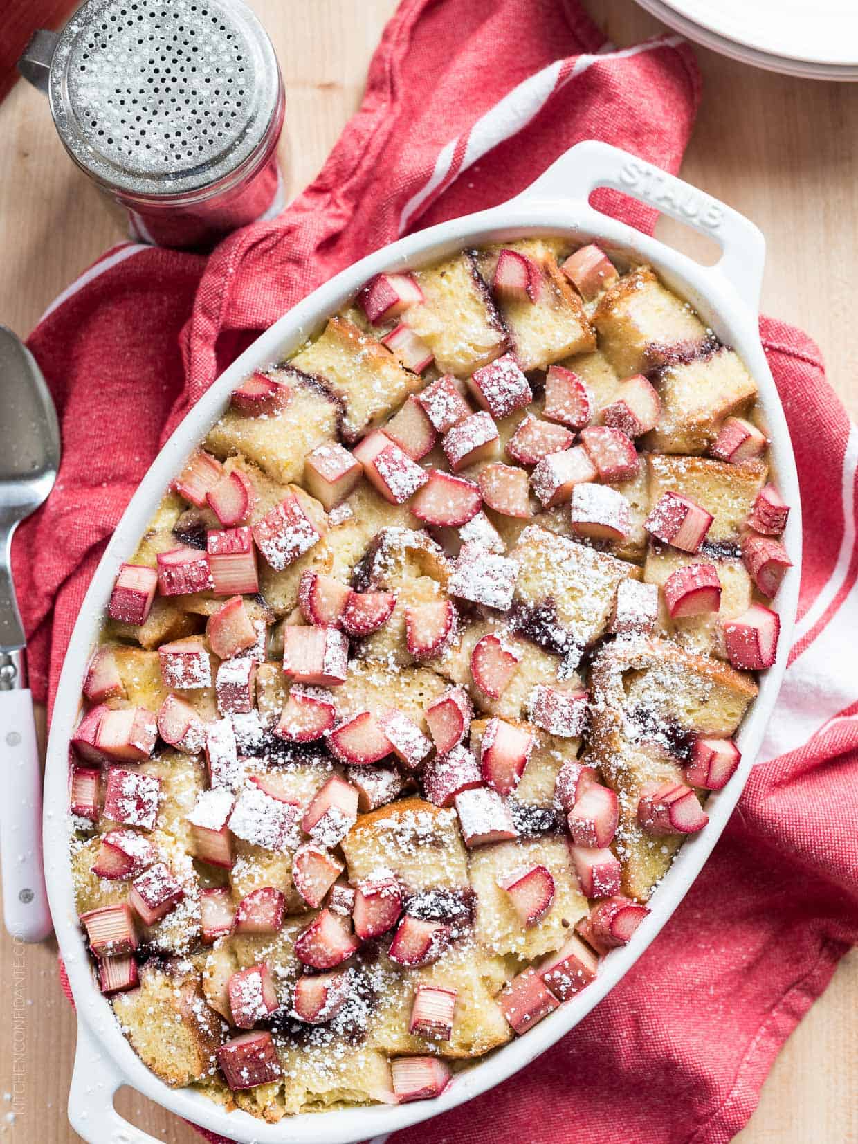 Rhubarb Breading Pudding in a white baking dish on a red and white cloth napkin.