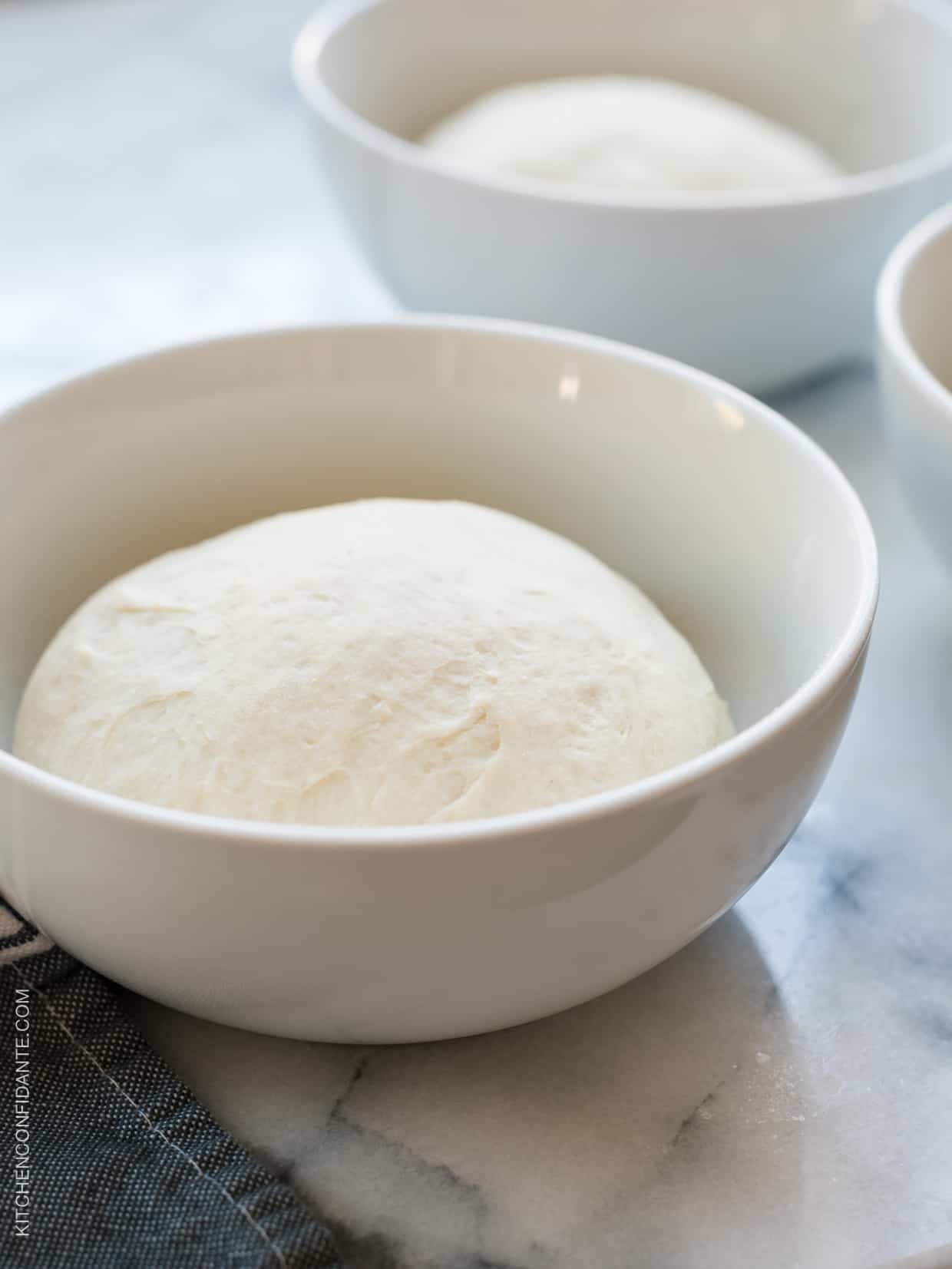 Olive oil flatbread dough in a white bowl.