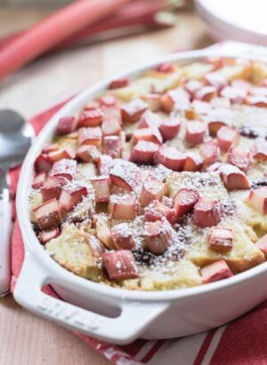 Rhubarb Breading Pudding in a white baking dish on a red and white cloth napkin.