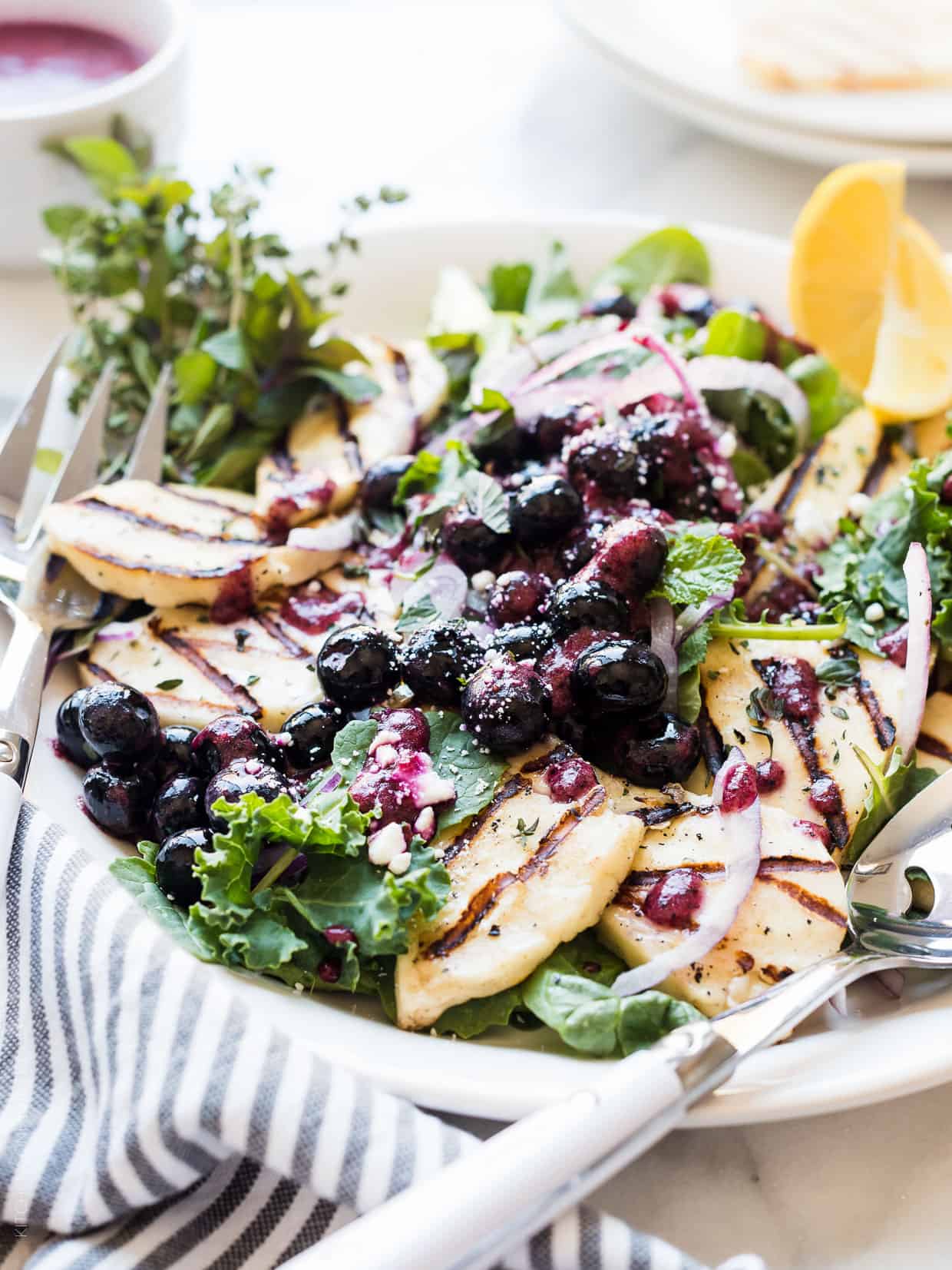 Grilled halloumi cheese served on top of a mixed green salad with a fresh blueberry dressing.