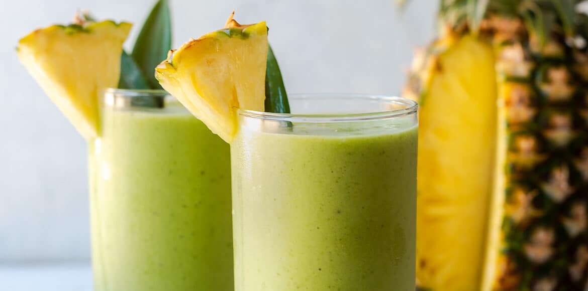 Piña Colada Green Smoothies in glasses garnished with fresh pineapple.
