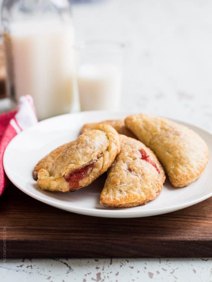 White plate with four small rhubarb empanadas on it.