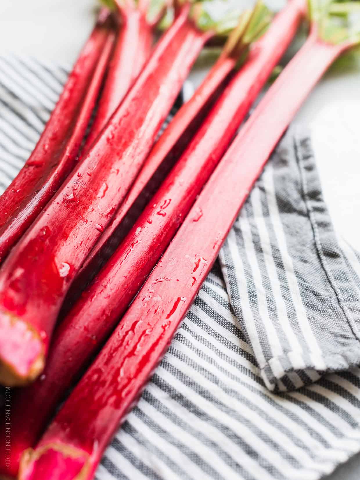 Stalks of freshly washed rhubarb on a blue and white striped towel.