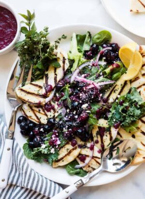 Grilled halloumi cheese served on top of a mixed green salad with a fresh blueberry dressing.