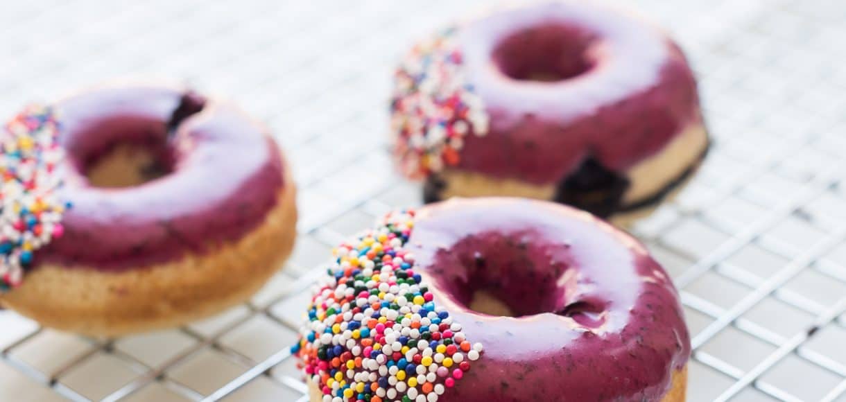 Blueberry glazed doughnuts on a cooling rack.