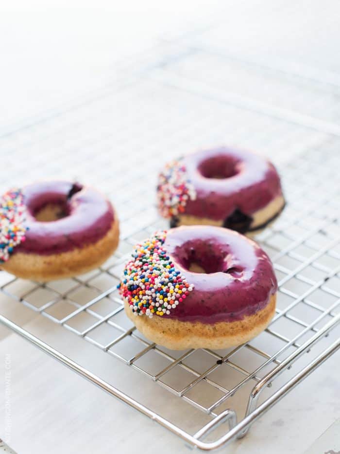Blueberry glazed doughnuts on a cooling rack.