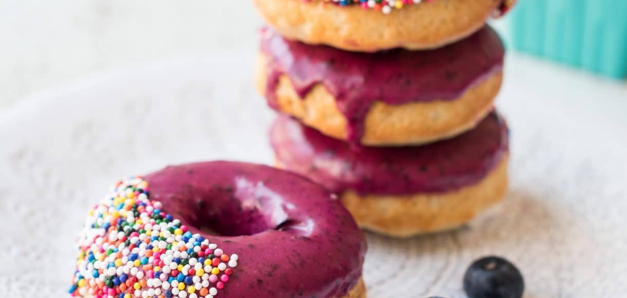 Stack of Baked Blueberry Donuts with Blueberry Lemon Glaze on a white plate.