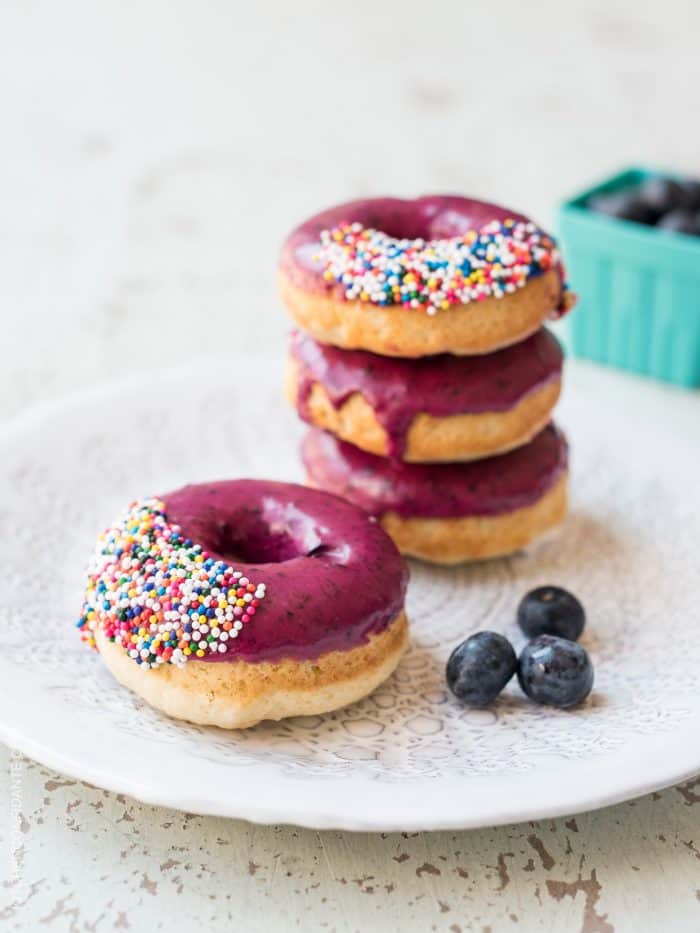 Stack of Baked Blueberry Donuts with Blueberry Lemon Glaze on a white plate.