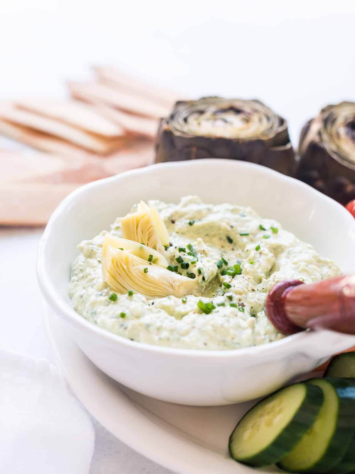 White bowl filled with Avocado and Artichoke Dip.