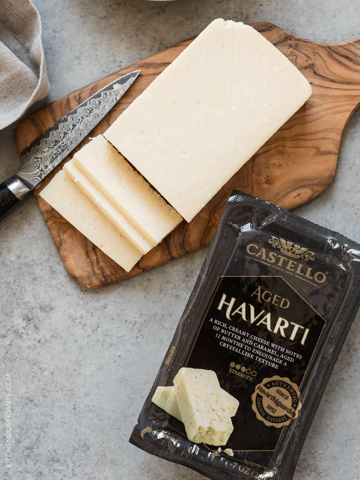 Sliced Havarti cheese on a cheese board.