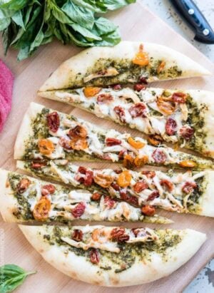 Chicken Pesto Pizza sliced on a cutting board.