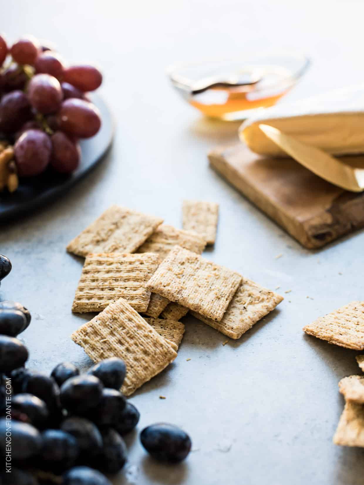 Triscuit crackers and grapes on a rustic surface.