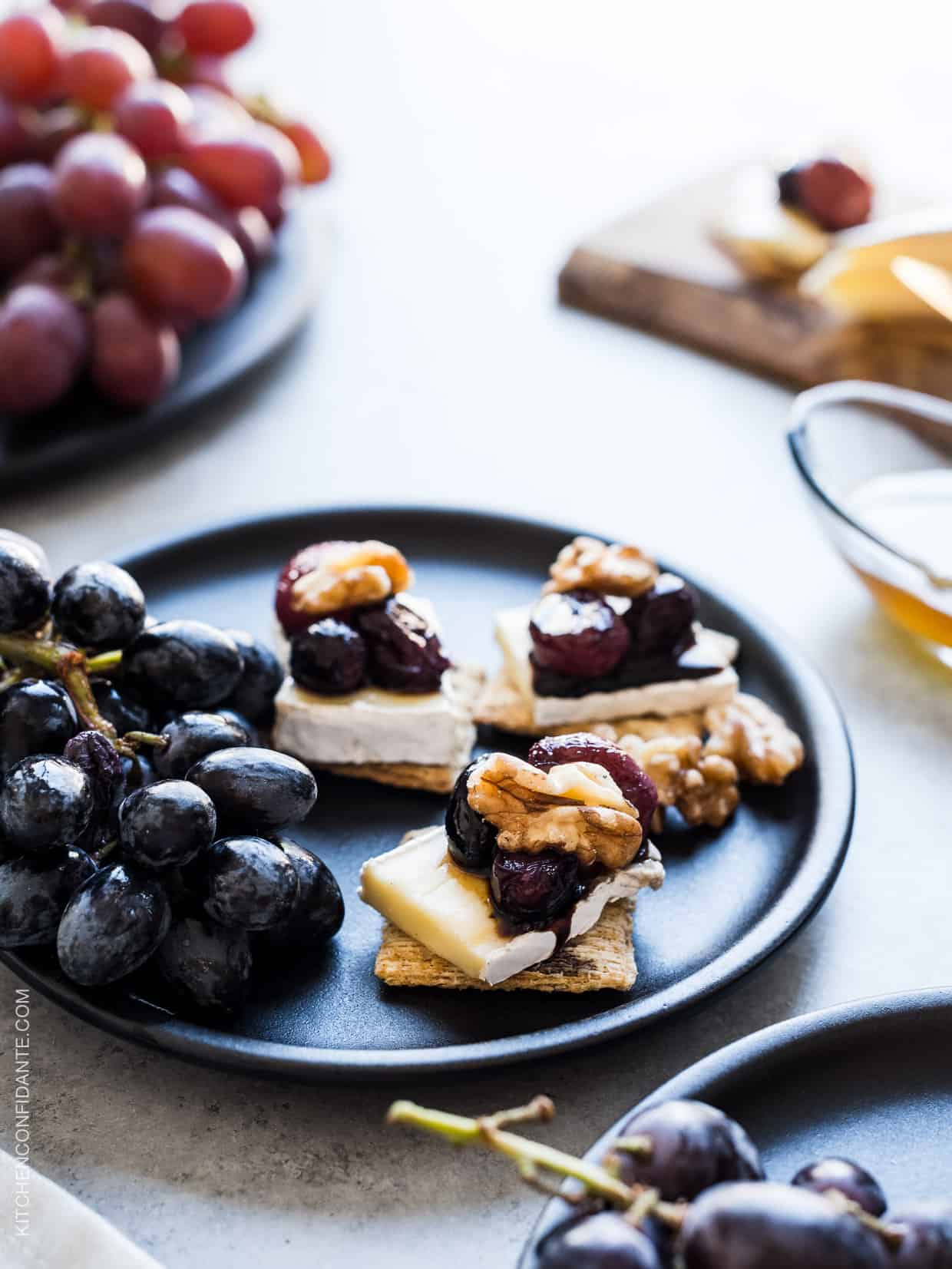 Close up view of Caramelized Grape, Brie and Walnut Bites made with TRISCUIT crackers and served on a plate.