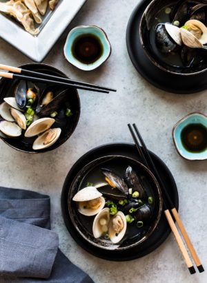 Three black bowls filled with Clam and Mussel Miso Soup and served with chopsticks.