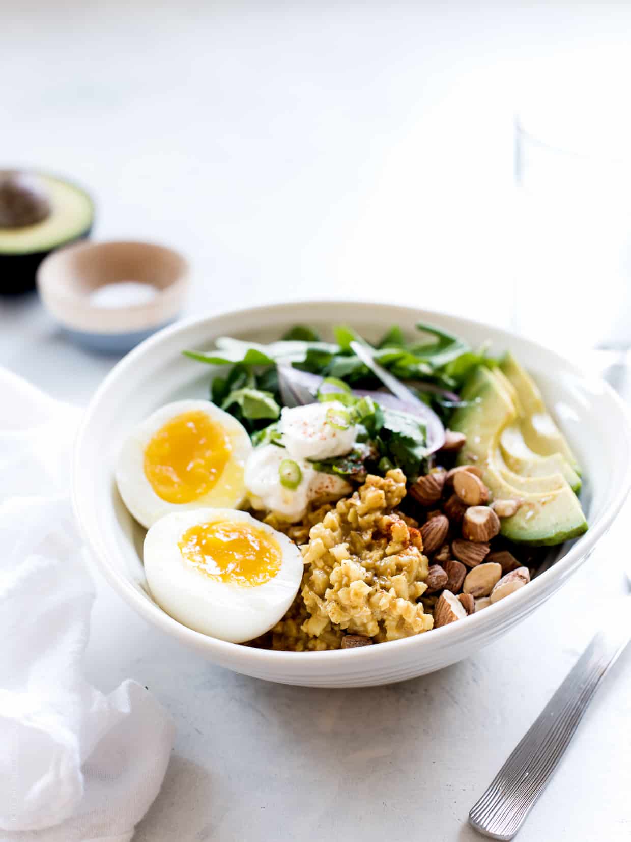 Coconut Curry Cauliflower Rice Bowls topped with eggs and avocado slices.