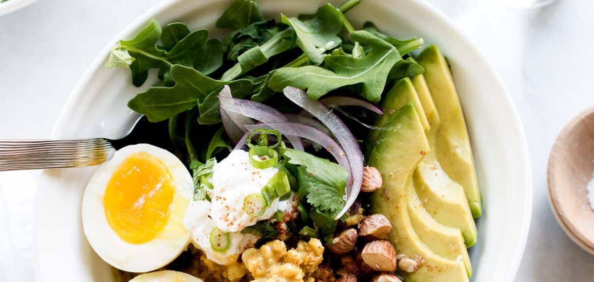 Coconut Curry Cauliflower Rice Bowls topped with eggs and avocado slices.