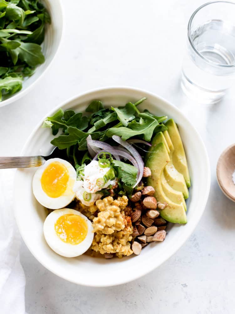 Coconut Curry Cauliflower Rice Bowls topped with eggs and avocado slices.