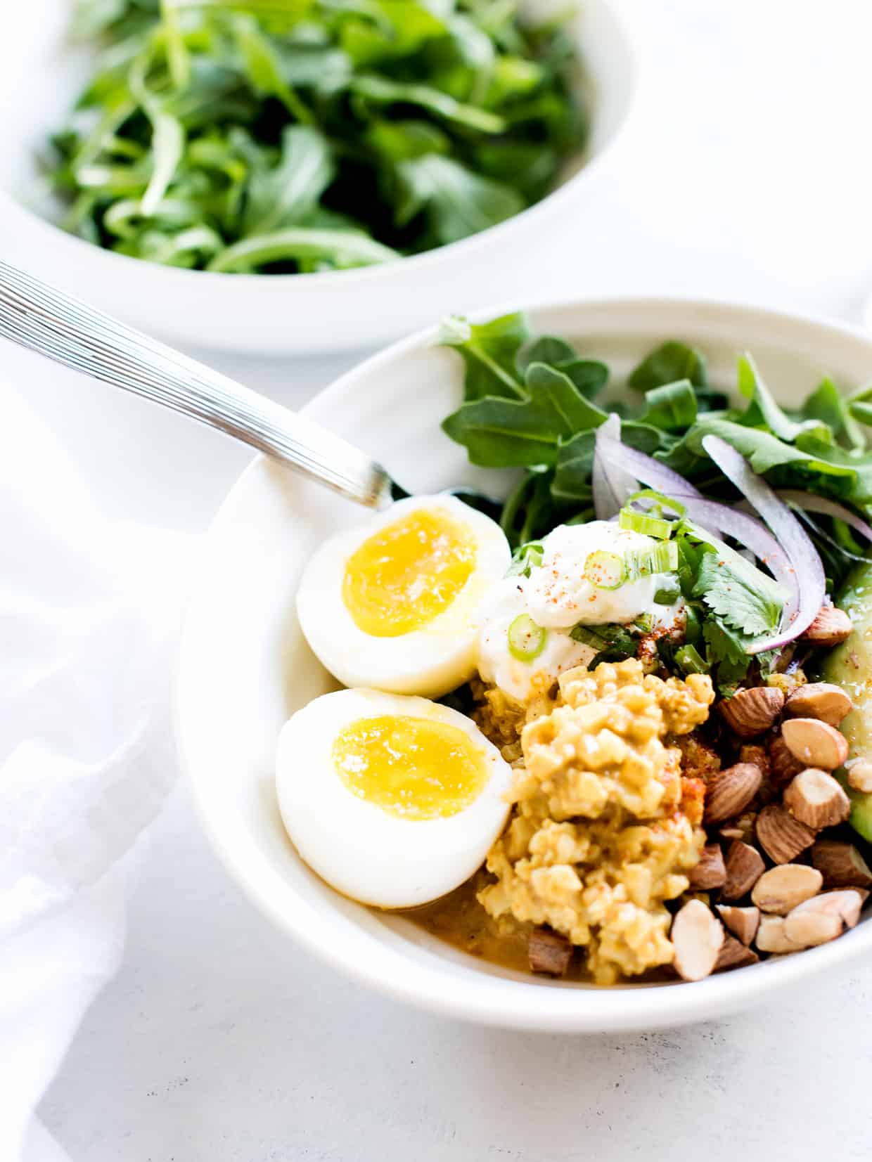 Coconut Curry Cauliflower Rice served in a bowl with almonds and eggs on top.