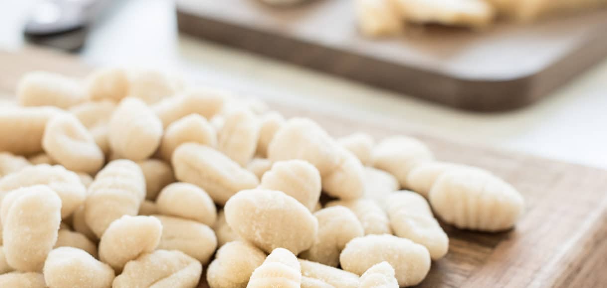 Fresh gnocchi on a wooden cutting board.