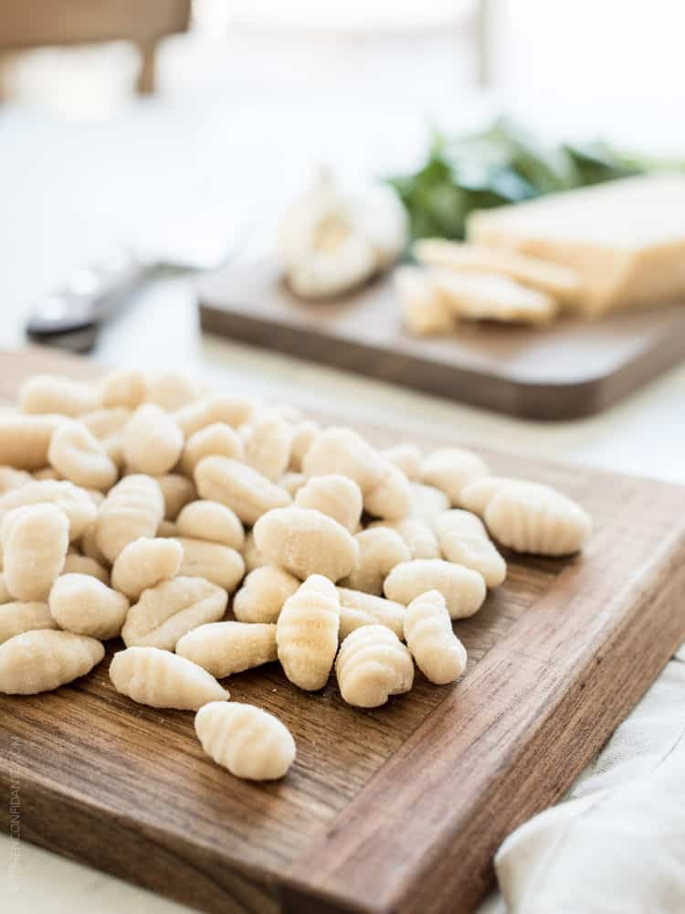 Fresh gnocchi on a wooden cutting board.