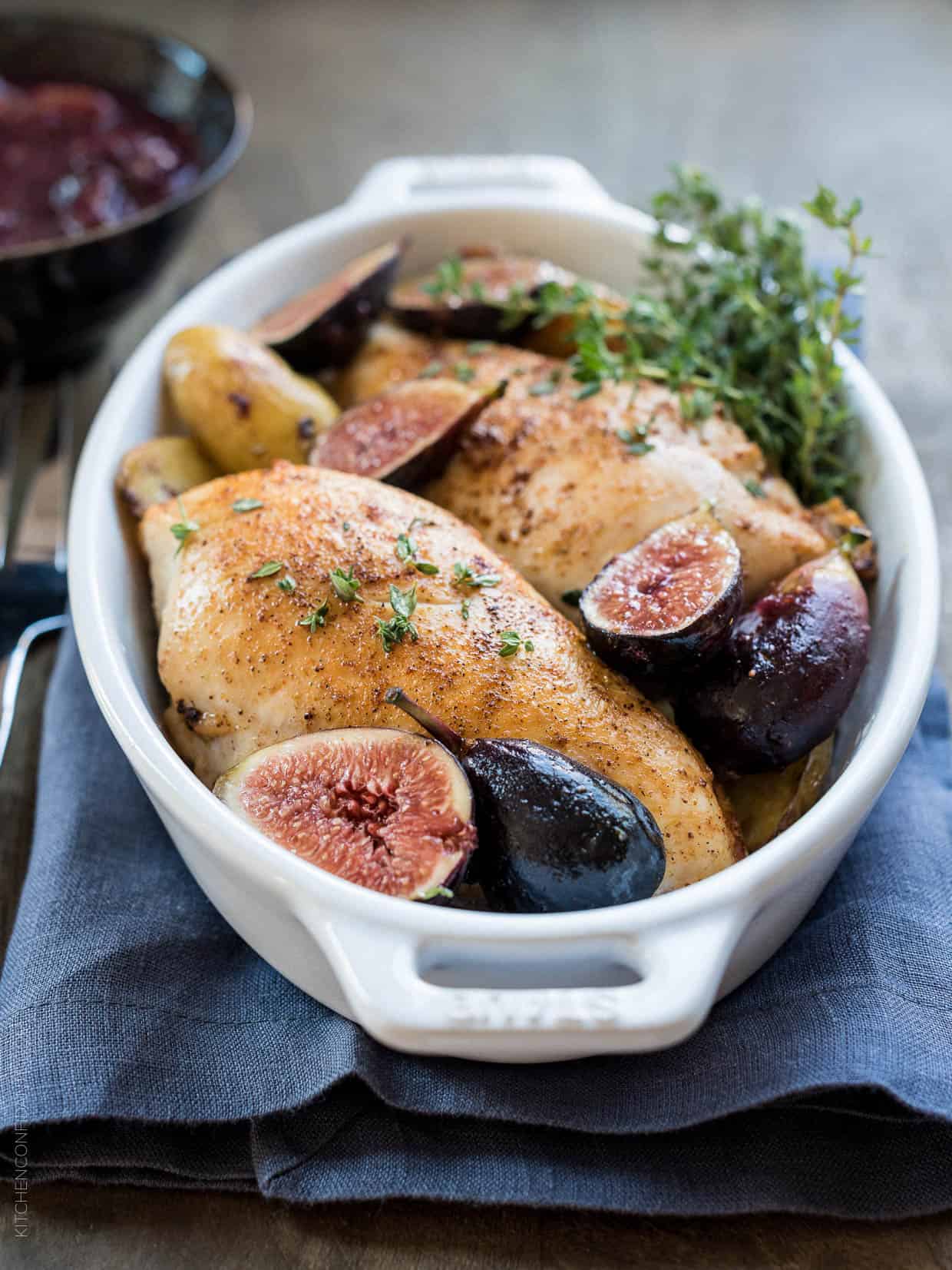 Chicken roasted in a white baking dish with fig chutney. 