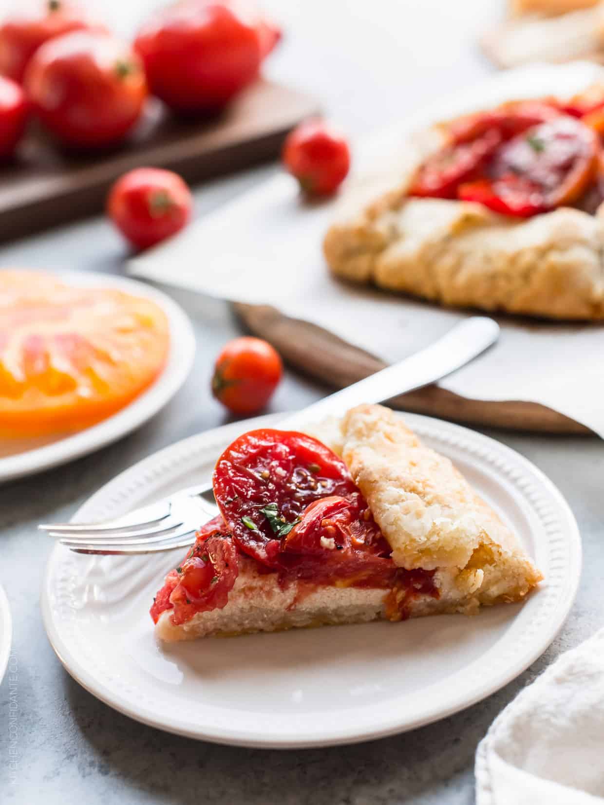 A slice of Tomato Ricotta Galette on a white place with a fork.