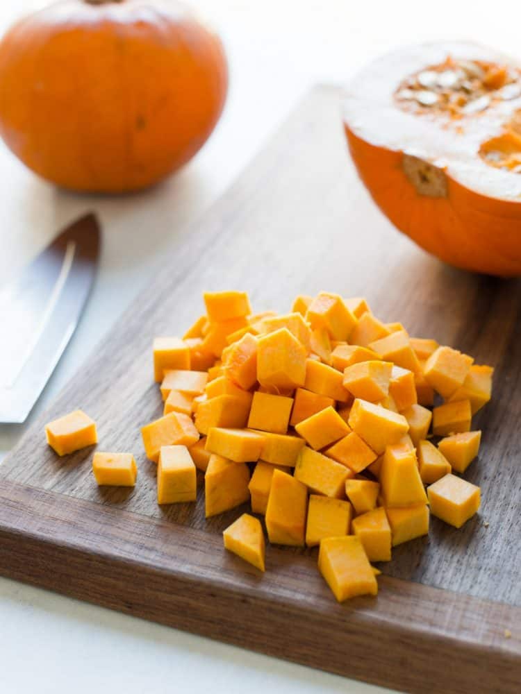 Diced fresh pumpkin on a wooden cutting board.