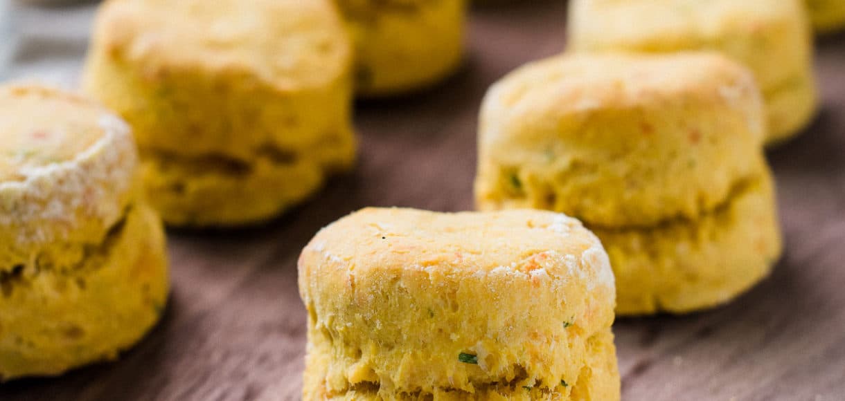 Freshly baked Pumpkin Cheddar Biscuits on a wooden serving board.