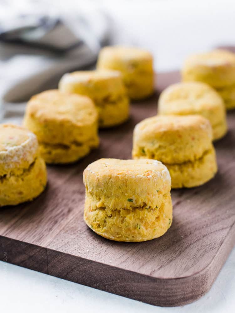 Freshly baked Pumpkin Cheddar Biscuits on a wooden serving board.