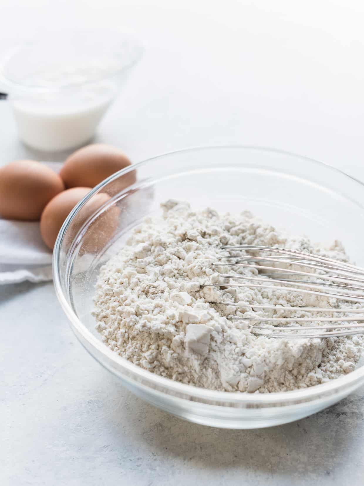 Dry ingredients for spaetzle in a glass bowl with a whisk.